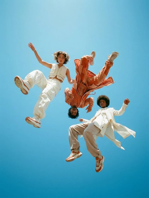 Reference image: three people in cream and orange outfits jumping against a blue sky
